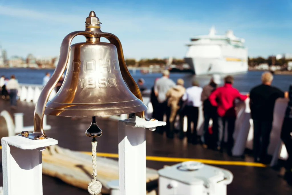 Clear view of a cruise ship with a bell in the foreground on a sunny day.