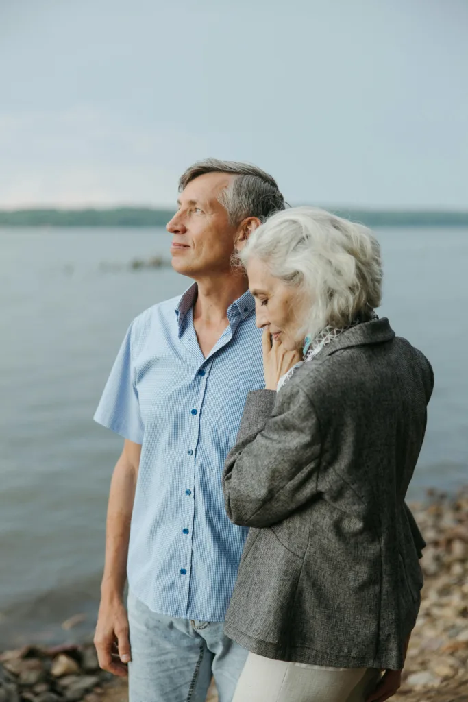 A peaceful moment of affection as a senior couple embraces by a serene lakeside.