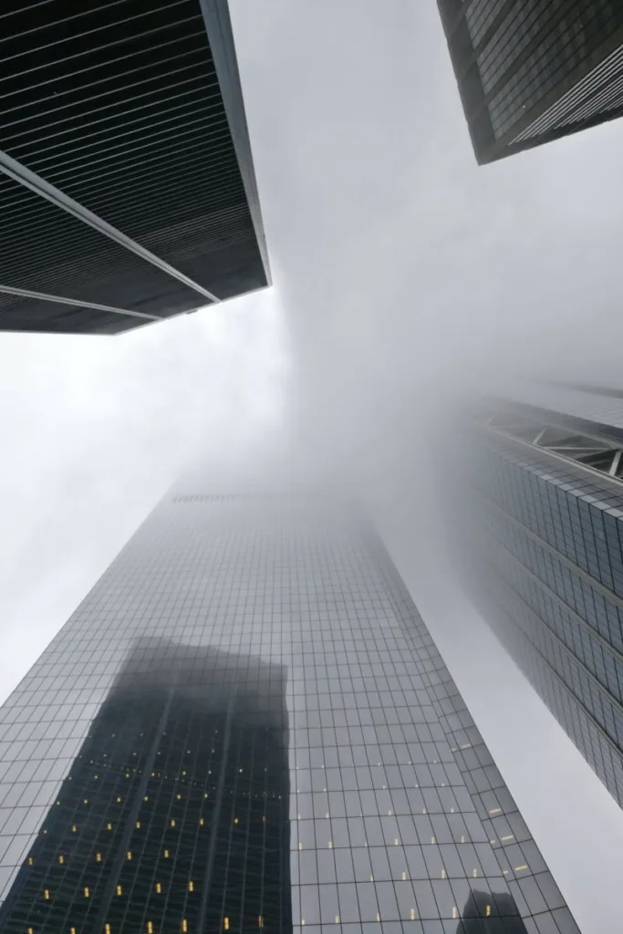 Dramatic view of skyscrapers disappearing into fog in New York City, showcasing urban architecture.